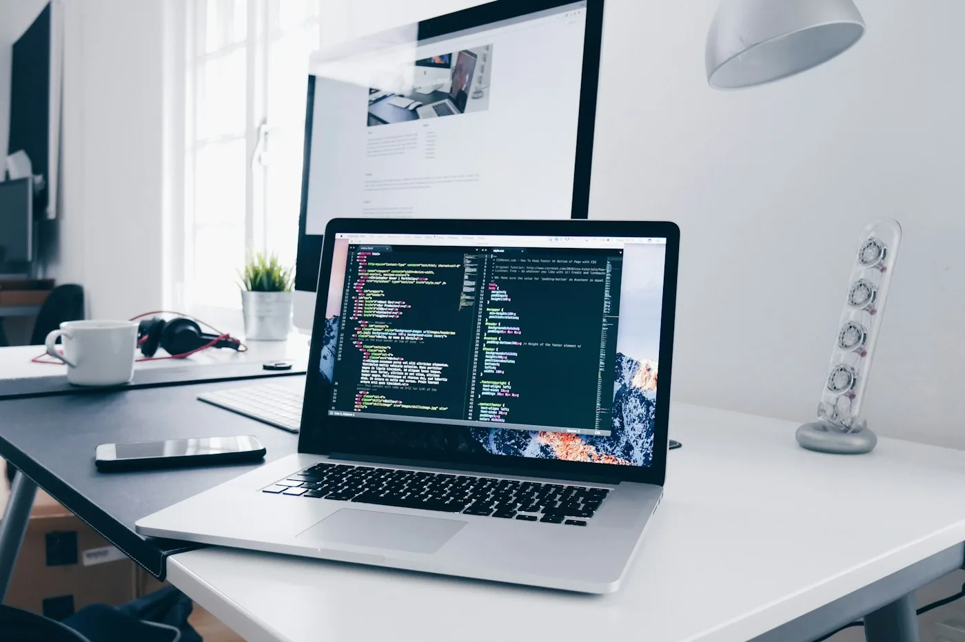 A laptop displaying source code at a desk.