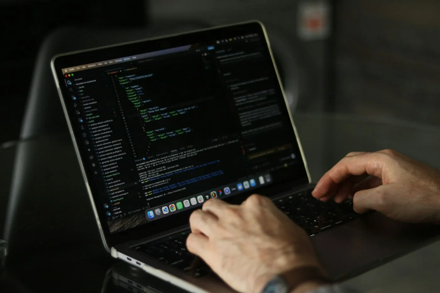 Hands typing source code on a laptop.