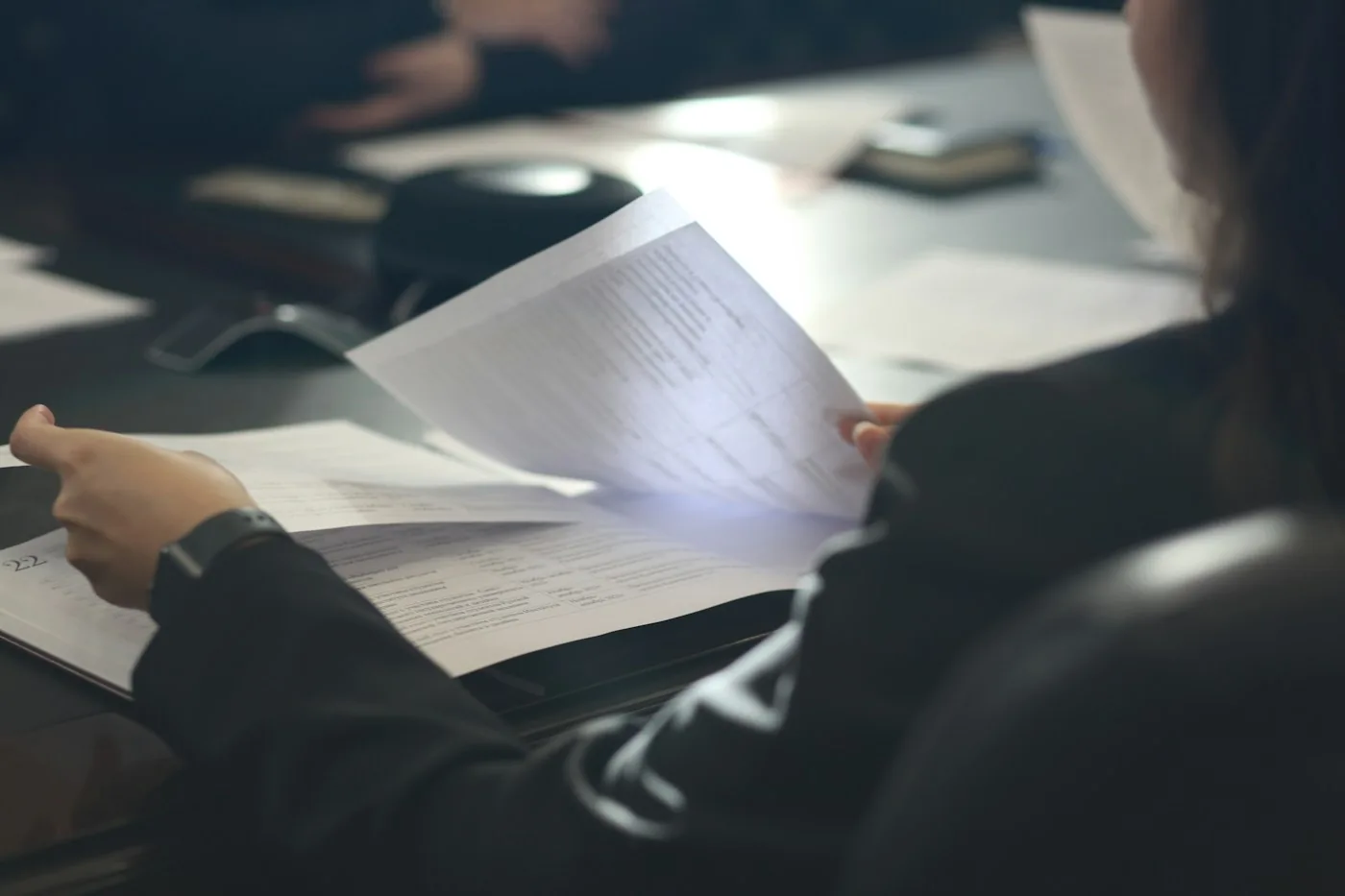 A professional reading a document at a desk.