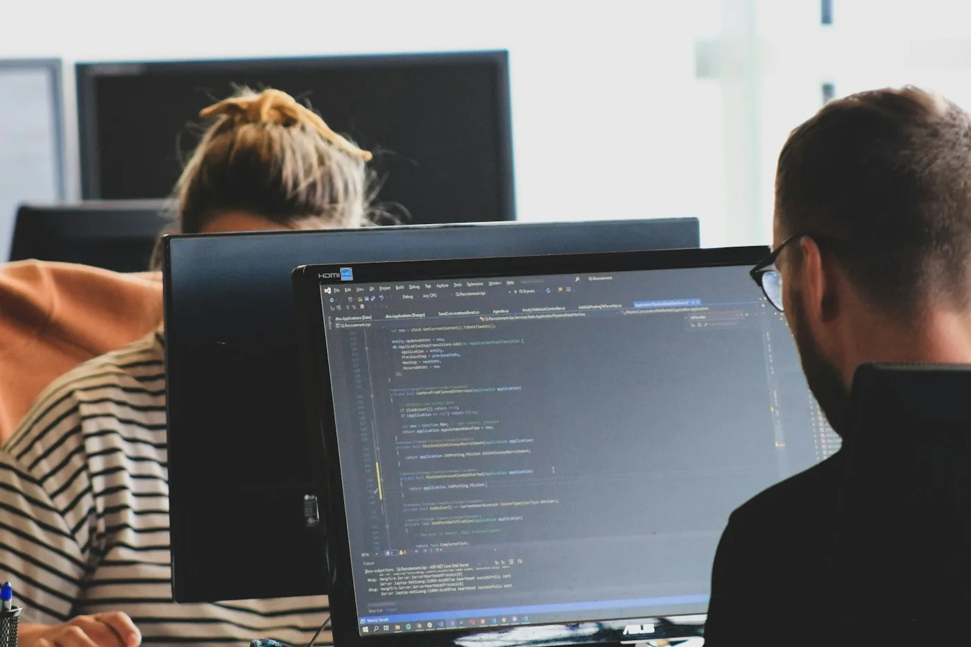 Two developers reviewing code on a computer.