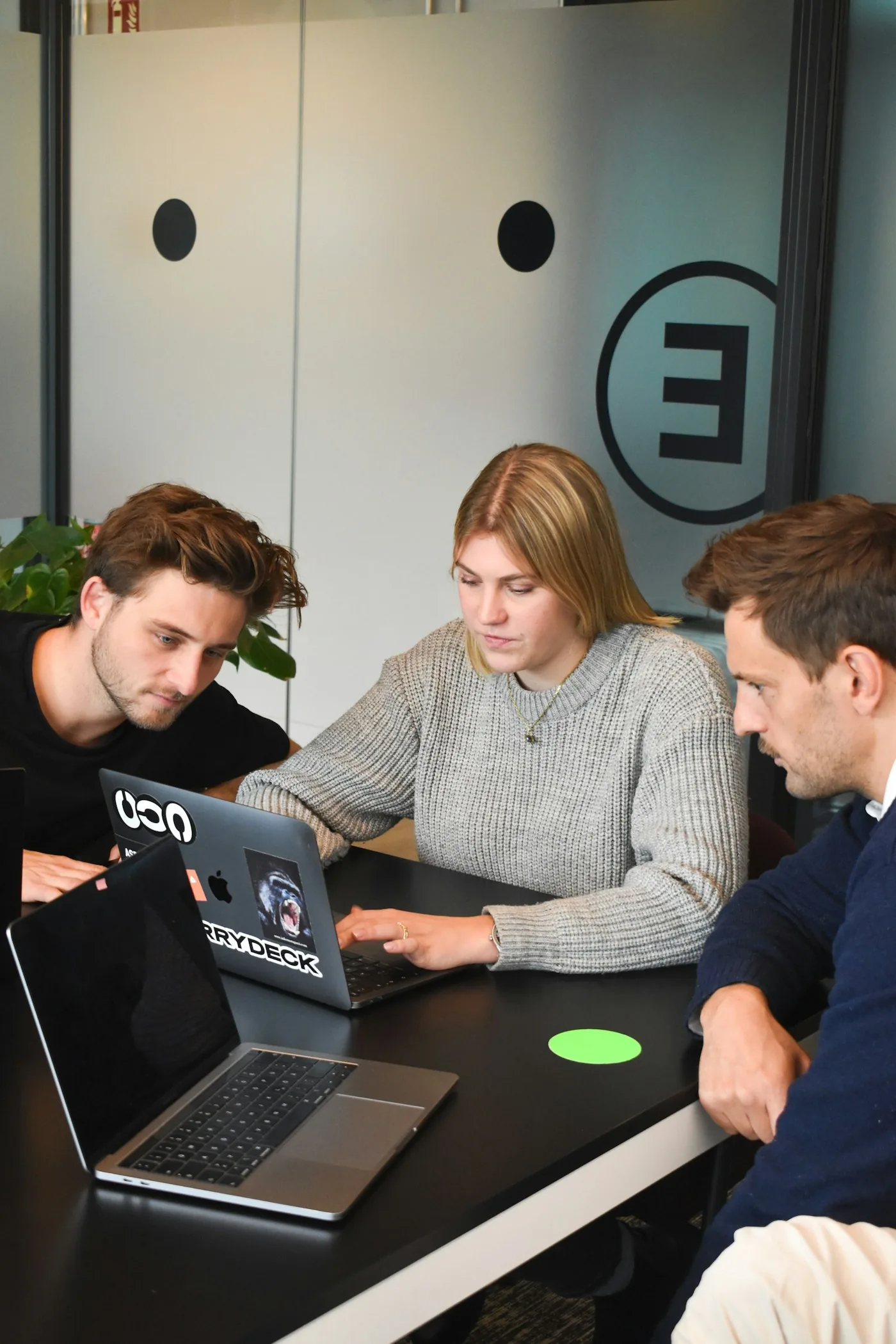 Three colleagues reviewing a laptop together.