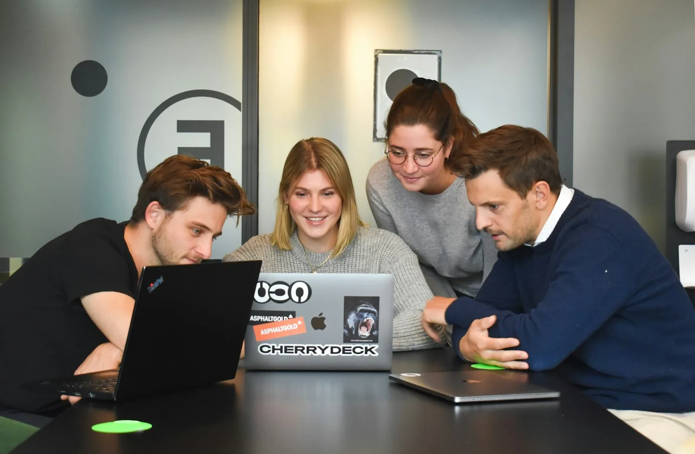 Four colleagues collaborating around a laptop.